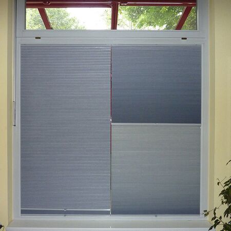 Plissee am Fenster als moderner Sicht- und Sonnenschutz in hellgrauer Farbe montiert.