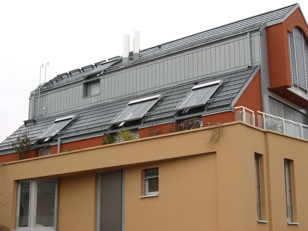 Modernes Wohnhaus mit Flachdach, Solarpanels und großen Fenstern für Energieeffizienz.